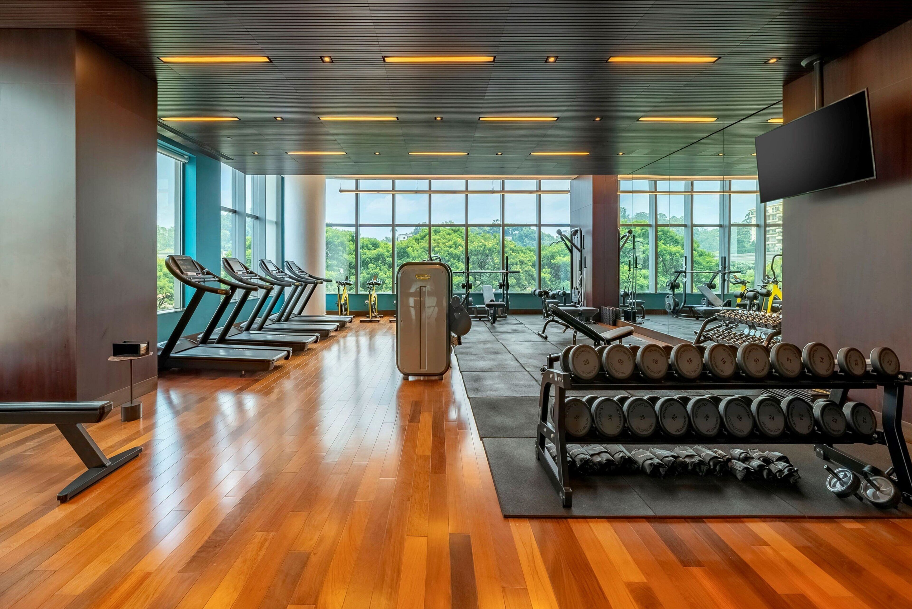 Une salle de sport équipée de tapis de course, d’appareils de musculation et d’haltères.