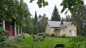 Ein Haus mit Garten, einem Esstisch mit Stühlen und einer roten Scheune.