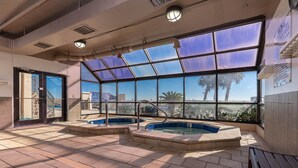 An indoor swimming pool area with clear views of palm trees and a building outside. - Phoenix East 1003 - Beautiful 2 BR Condo (Orange Beach)