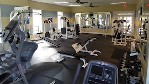 A gym with various exercise equipment, including treadmills, weight machines, and free weights.