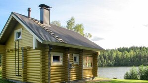 A log cabin with a metal roof, two chimneys, and a small porch.