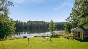 A serene lakeside setting with a gazebo, a small table, and two chairs.
