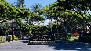 Une enseigne indiquant l’emplacement de Waikoloa Beach Villas, offrant une vue dégagée sur la végétation et les bâtiments environnants.