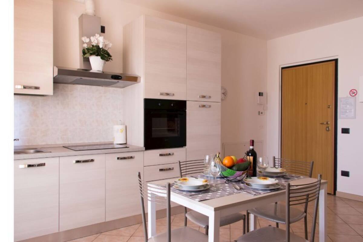 Une cuisine moderne avec des meubles blancs, un four noir et une table à manger dressée pour deux personnes.