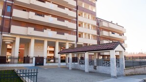 A multi-story residential building with balconies, a covered outdoor seating area, and a paved courtyard. - Residence Le Groane (Garbagnate Milanese)