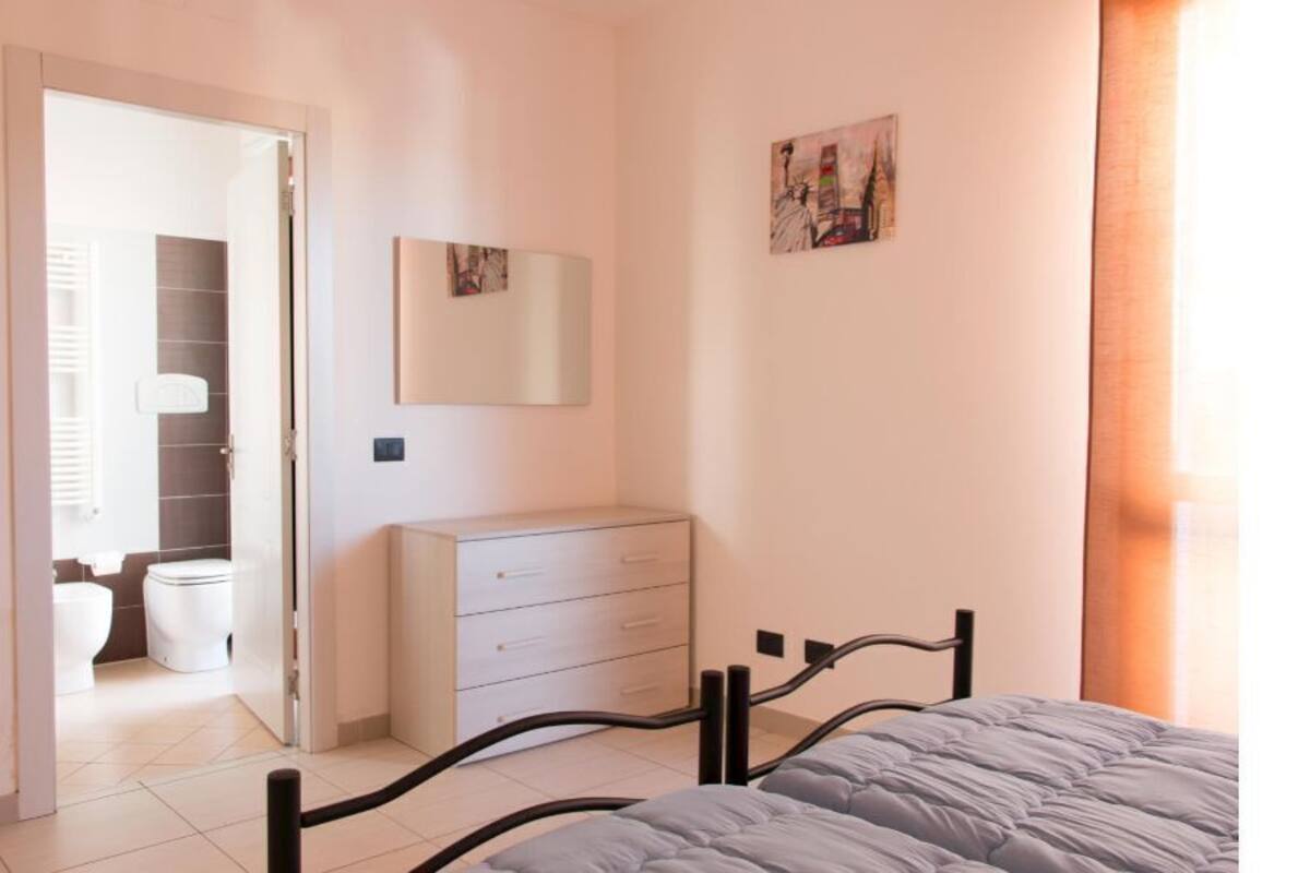 Une chambre à coucher comprenant un lit, une commode et une porte donnant sur une salle de bain.