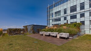 A modern building with a glass facade, a wooden deck with outdoor seating, and a well-maintained lawn. - Bluebird Suites near MIT (Cambridge)