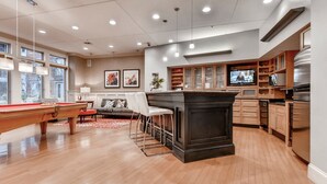 A spacious living area with a pool table, a sofa, and a kitchen with modern appliances. - Bluebird Suites in Downtown Providence (Providence)