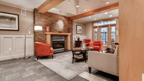 A living room with a fireplace, two orange armchairs, a beige sofa, and a coffee table. - Bluebird Suites in Downtown Providence (Providence)
