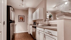 A modern kitchen with white cabinets, stainless steel appliances, and a wooden floor. - Bluebird Suites in Downtown Providence (Providence)