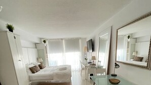 A hotel room with a bed, a desk, a chair, a wardrobe, and a large mirror. - Stay at Brickell by Executive Corporate Rental (Miami)