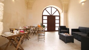 A dining area with a high arched doorway, wooden tables, and chairs. - Corte Manzoni B&B (Melendugno)
