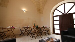 A dining area with tables and chairs, a large arched doorway, and a stone ceiling. - Corte Manzoni B&B (Melendugno)