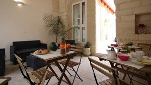 An outdoor dining area with a table set for two, a sofa, and a potted plant. - Corte Manzoni B&B (Melendugno)