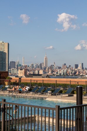 A rooftop pool with lounge chairs and a city skyline in the background. - Bluebird Suites near Newport Center (Jersey City)