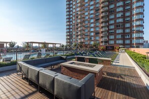A rooftop pool area with lounge seating and a fire pit. - Bluebird Suites near Newport Center (Jersey City)