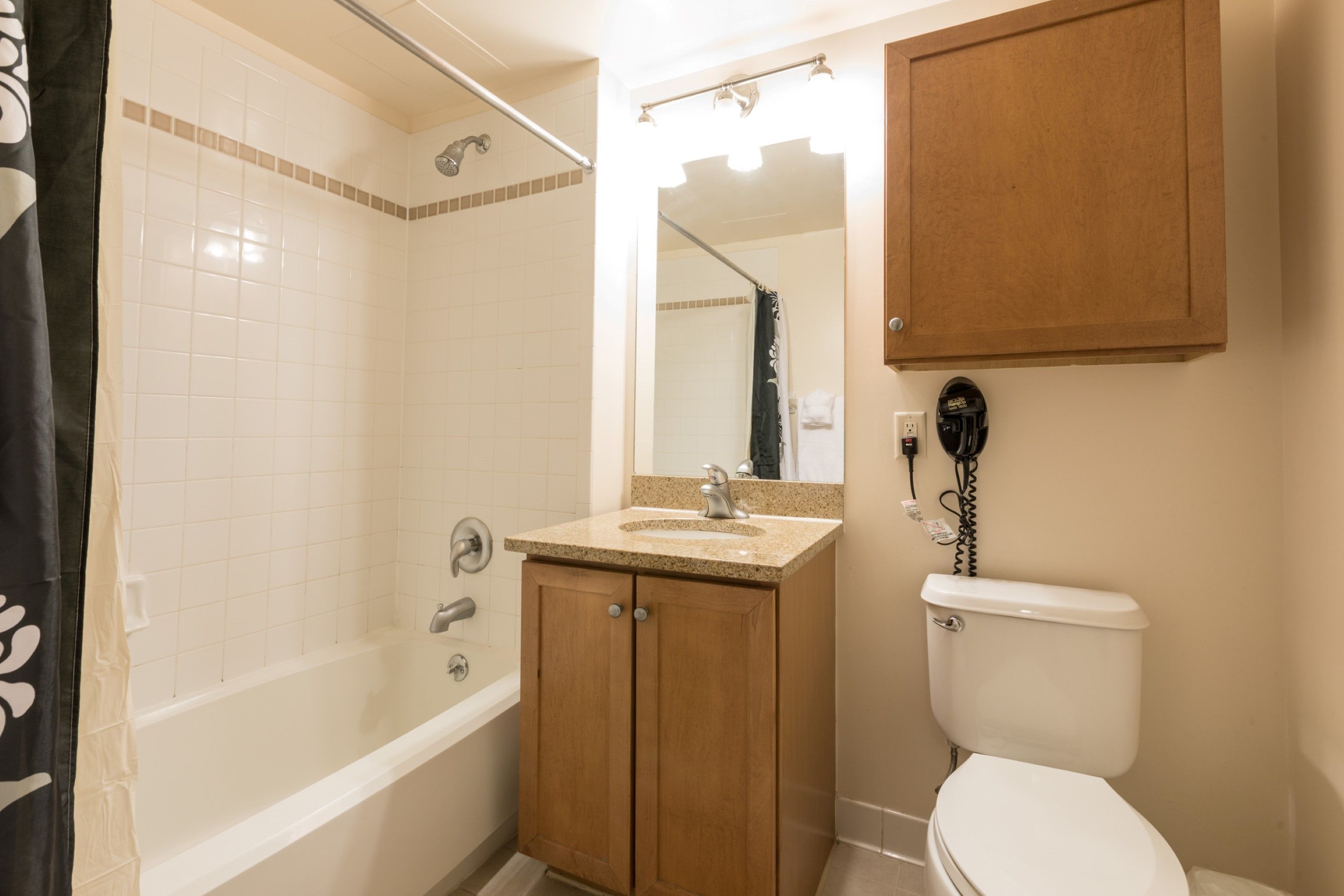 Un baño con bañera, lavamanos con espejo y retrete.