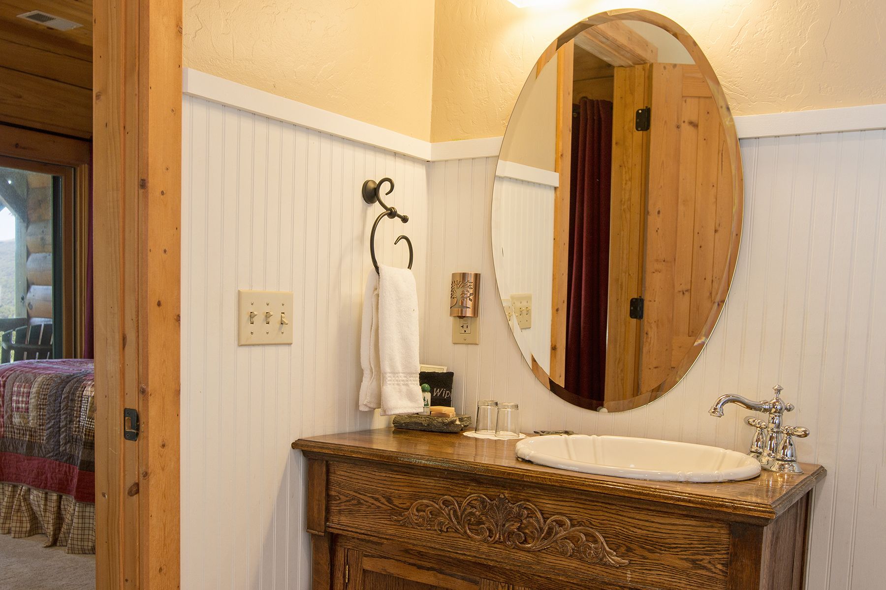 Un bagno con un mobile vanitario in legno, un ampio specchio ovale e un lavandino bianco.