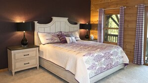 A bedroom with a wooden headboard bed, two bedside tables with lamps, a nightstand, and a window with curtains. - Lazy Bear Lodge (Vilas)