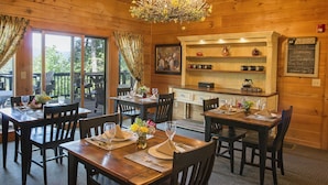 A cozy wooden dining area with tables set for two, a chandelier, and a chalkboard menu on the wall. - Lazy Bear Lodge (Vilas)