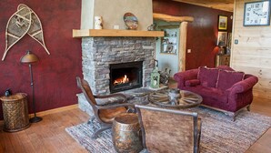 A cozy living room with a stone fireplace, a red couch, a wooden coffee table, and a rustic decor style. - Lazy Bear Lodge (Vilas)