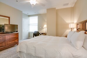 A hotel room with a large bed, a wooden dresser, a desk, and a television.