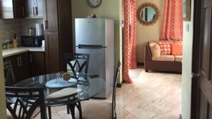 A compact kitchen with a refrigerator, microwave, and dining table with chairs. - Believe Caribbean Apartments (Bridgetown)