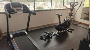 Un gimnasio con cinta de correr, elíptica y bicicleta estática.