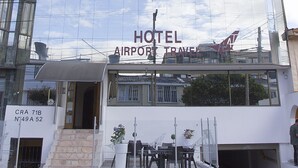 Un hotel moderno con fachada de vidrio reflectante, entrada visible y señal que indica que es un hotel del aeropuerto.