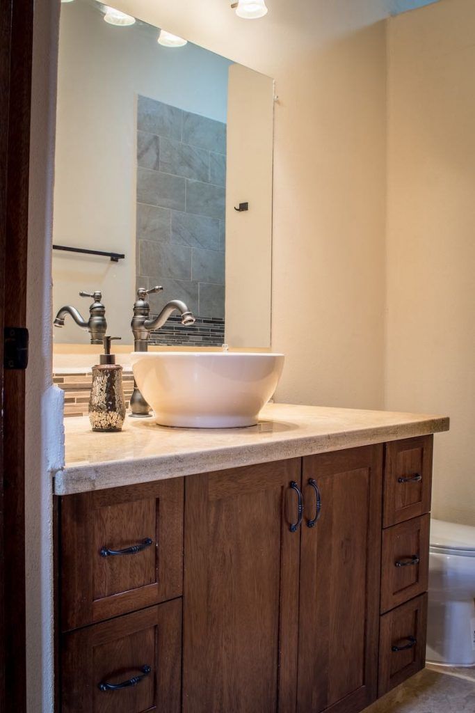 Un baño con un lavabo de pedestal grande, armarios de madera y un espejo sobre el lavabo.