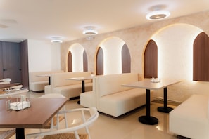 Ein modernes Restaurant mit weißer Möbel, eingelassener Beleuchtung und Wandgestaltung mit Bögen.
