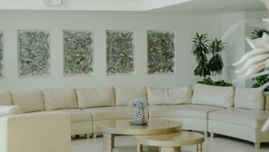 Een ruime woonkamer met een grote hoekbank, een ronde salontafel en een kroonluchter.