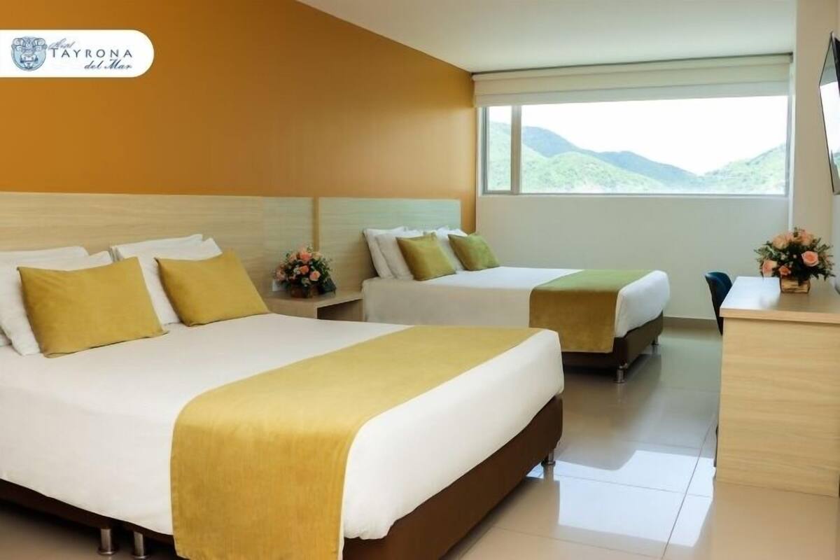 A hotel room with two beds, a desk, and a view of the mountains.