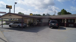 Un motel con zona de estacionamiento techada, un letrero de Sonic Drive-In y una tienda AutoZone visible al fondo.