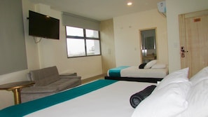 A hotel room with a bed, a sofa, a TV, a window, and a door.