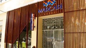 L’extérieur de l’hôtel Marcapoi se caractérise par une façade moderne, une entrée en verre et un portail en métal.