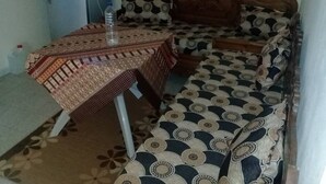A small, cozy room with a sofa and a table, both covered with patterned fabric. - Studio Pour Vacance A Hammam Al Ghezéze (Hammam Al Agzaz)