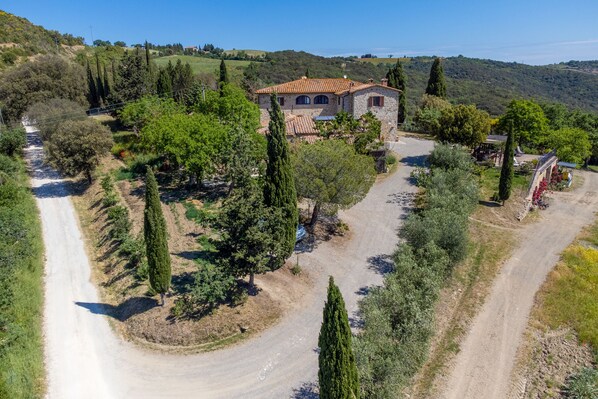 A stone house with a tiled roof surrounded by trees and a dirt road. - Agriturismo Il Poderuccio (Castiglione d'Orcia)