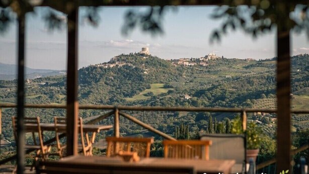 Vista panorámica desde un balcón con vistas a una colina con edificios y vegetación.