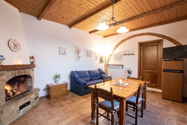 Una sala de estar acogedora con chimenea, una mesa de comedor y un sofá azul.