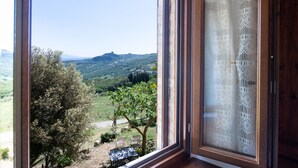 Una habitación con un amplio ventanal que ofrece vistas a un paisaje montañoso con árboles y una colina distante.