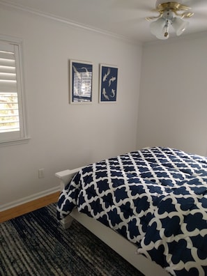 A bedroom with a bed, a ceiling fan, and two wall-mounted pictures. - University City Guest House (Charlotte)