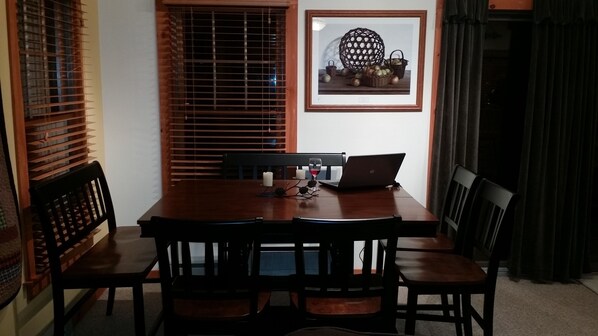 A dining area with a wooden table, four chairs, a laptop, candles, and a framed picture on the wall. - Beautiful home, hot tub, across from Camelback Resort (Tannersville)