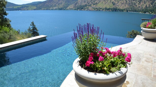 Vista despejada de una piscina con montañas al fondo y una jardinera con flores en primer plano.