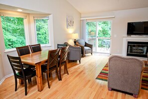 A spacious living area with a dining table, chairs, a sofa, a TV, and a fireplace.