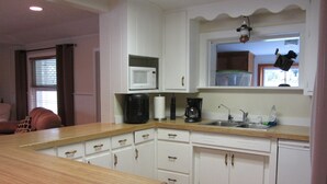 A kitchen with white cabinets, a wooden countertop, a microwave, a coffee maker, and a window with a view of the outside. - Huge Private Sandy Beach! Sleeps 22! Private Suites! Some Aug/Sept Availability! (Onaway)