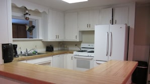 A kitchen with white cabinets, a wooden countertop, a stove, a refrigerator, and a sink. - Huge Private Sandy Beach! Sleeps 22! Private Suites! Some Aug/Sept Availability! (Onaway)