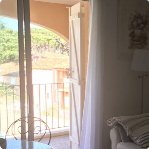 Une pièce avec un balcon, une chaise en métal et un canapé.
