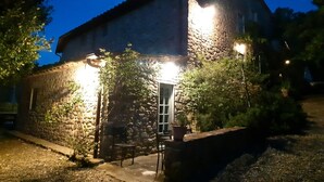 A stone building with a door and a small patio area with a table and chairs. - Charm, comfort, relax at il Bracconiere, part of il Cavato, typical farmhouse
, (Poggio Alla Croce)