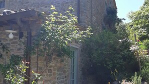 A stone building with a rustic exterior, a small table with chairs, and potted plants. - Charm, comfort, relax at il Bracconiere, part of il Cavato, typical farmhouse
, (Poggio Alla Croce)